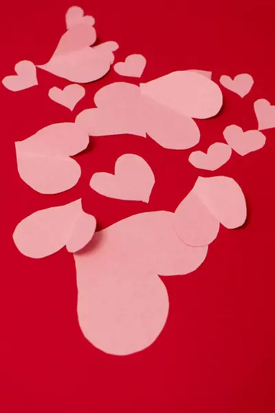 Kırmızı arka planda birkaç pembe kalp. Sevgililer Günü konsepti. Dikey