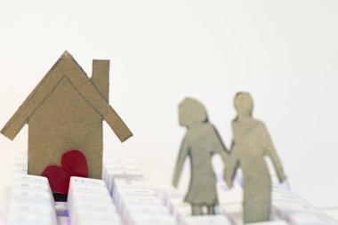 Beyaz arka planda kırmızı kalpli ve ailesi olan kağıt ev. Aşk konsepti.