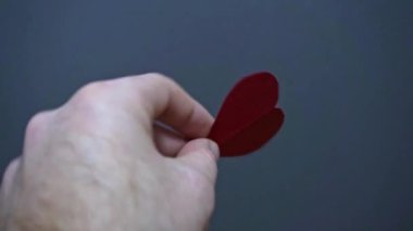 Kağıt kalp gösteren bir insan eli.