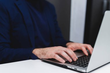 İş yerinde dizüstü bilgisayarda daktilo kullanan işadamının kırpılmış görüntüsü.