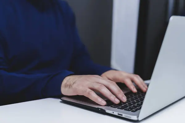 Ofisteki dizüstü bilgisayarda daktilo eden erkek ellerinin yakın çekimi..