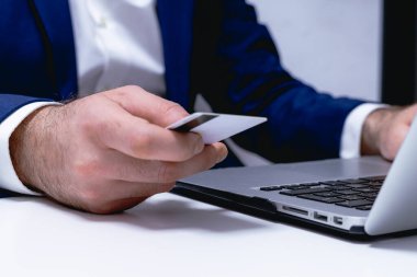 Kredi kartı tutan ve dizüstü bilgisayar kullanan erkeklerin fotoğraflarını çek. Çevrimiçi alışveriş kavramı