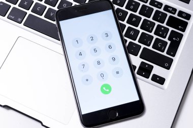Laptop ve akıllı telefon beyaz arkaplanda. Yukarıdan bak. Telefon numaraları var.