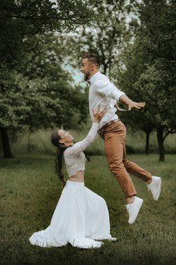 Mutlu genç çift yaz günü çimlerin üzerinde dans ediyor.