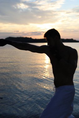 Denizde dövüş sanatları yapan bir adamın silueti.