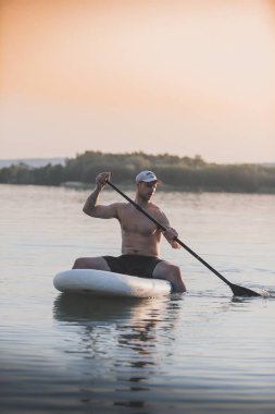 Gün batımında kürek tahtasında bir adam. Sakallı bir adam.