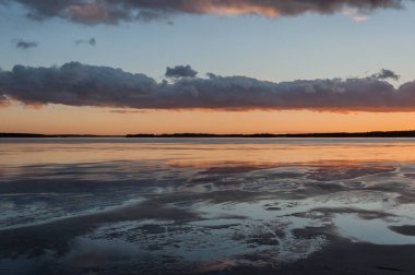 Finlandiya 'da kış sonlarında gün batımında gökyüzünde bulutlu donmuş göl manzarası