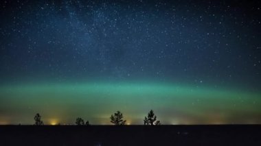 Yıldızlı gökyüzünün ağaç tepesi seviyesinden ve Finlandiya 'daki ormanların üzerindeki Aurora Borealis kavisinden zaman aşımı 