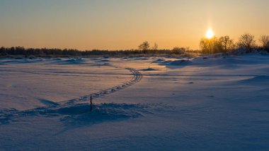 Kış deniz kıyısında güneşin batışı raylar ve kardaki balık tuzaklarıyla