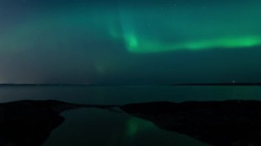 Aurora Borealis 'in zaman aşımı Tampere, Finlandiya' da sakin bir gölün yüzeyine yansımaktadır.