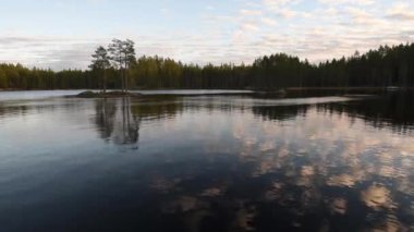 Finlandiya 'da, sonbaharda, ormanlarda göl kenarında sakin bir öğleden sonra, bulutlar yavaşça gökyüzünde sürüklenirken.