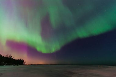 Tampere, Finlandiya 'daki donmuş göl üzerinde yeşil ve mor aurora borealis.