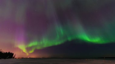 Tampere, Finlandiya 'daki donmuş göl üzerinde yeşil ve mor aurora borealis.
