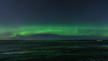 Tampere, Finlandiya 'da donmuş bir gölün üzerindeki yeşil aurora borealis.
