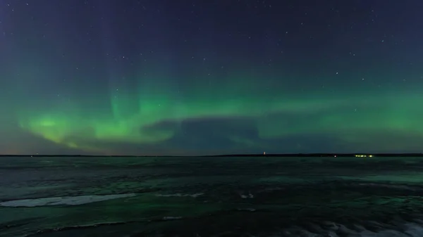 Tampere, Finlandiya 'da donmuş bir gölün üzerindeki yeşil aurora borealis.