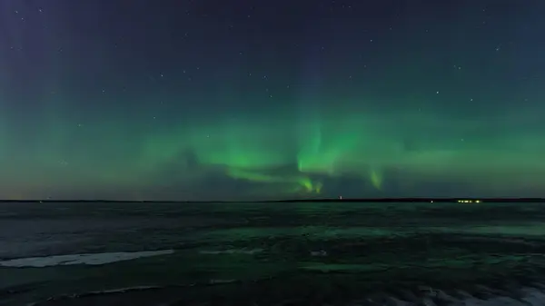 Tampere, Finlandiya 'da donmuş bir gölün üzerindeki yeşil aurora borealis.