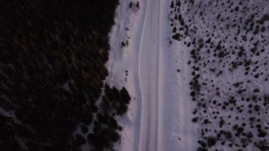 Kış akşamları Finnish ormanlarında küçük, karlı bir yolda insansız hava aracı uçuşu.