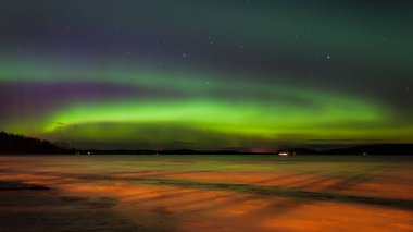 Finlandiya 'nın Pirkanmaa kentindeki donmuş bir gölün üzerinde buzu aydınlatan turuncu ışıkla Aurora Borealis.