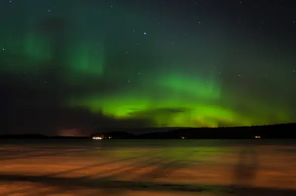 Finlandiya 'nın Pirkanmaa kentindeki donmuş bir gölün üzerinde buzu aydınlatan turuncu ışıkla Aurora Borealis.