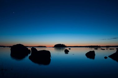 Finlandiya 'da ilkbaharda adalar ve kayalar ile gün batımından sonra deniz kıyılarının mavi renkleri