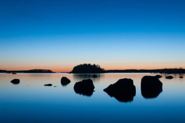 Finlandiya 'da ilkbaharda adalar ve kayalar ile gün batımından sonra deniz kıyılarının mavi renkleri