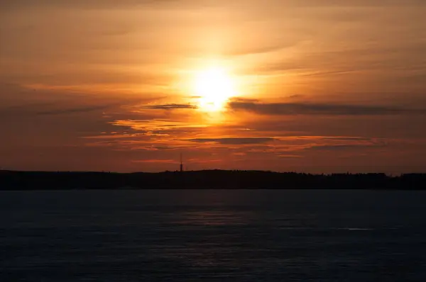 Finlandiya, Tampere 'de donmuş Nasijarvi gölünün üzerinde gün batımı ve ufukta orman var.