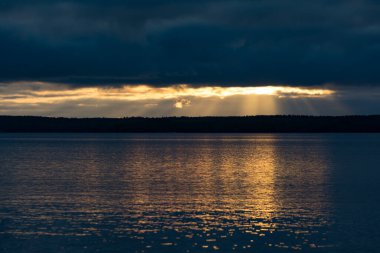 Yazın başında Nasijarvi, Tampere, Finlandiya 'da bir orman ve göl üzerinde parlayan ışık