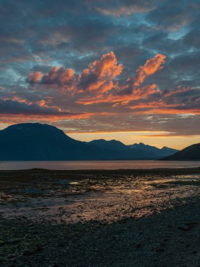 Gün batımında bulutlar dağların üzerinden ve Kuzey Norveç 'te fiyort renginde.