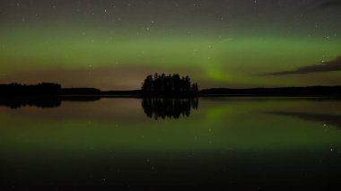 Finlandiya 'nın güneyinde sakin bir göl yüzeyine yansıyan ada ve aurora borealis renkleri