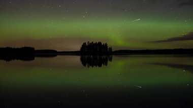 Finlandiya 'nın güneyinde sakin bir göl yüzeyine yansıyan ada ve aurora borealis renkleri