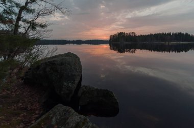 Günbatımı manzarası Güney Finlandiya 'da ormanların ortasında bir göl.