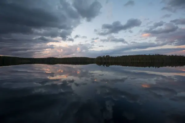 Finlandiya 'da sakin bir gölün yüzeyine yansıyan bulutlar ve ormanlar