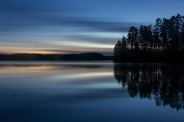 Finlandiya ormanlarında bahar gecesi sakin ve sakin bir göl.
