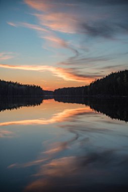 Finlandiya 'nın kozalaklı ormanlarında bahar akşamı günbatımında göl manzarası