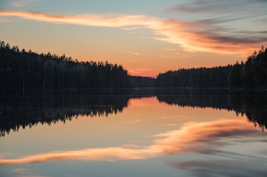 Finlandiya 'nın kozalaklı ormanlarında bahar akşamı günbatımında göl manzarası