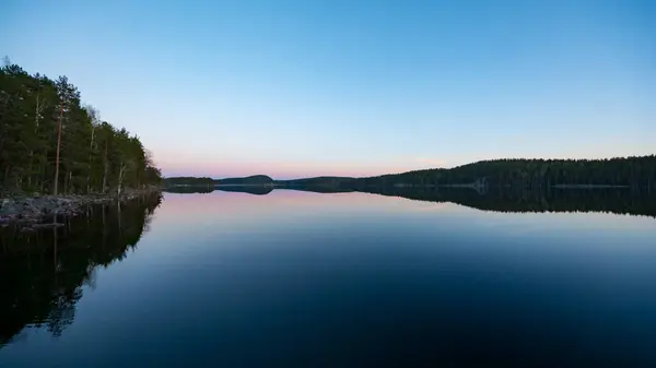 Finlandiya 'nın kozalaklı ormanlarında bahar akşamı günbatımında göl manzarası