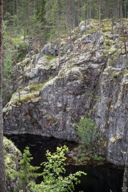 Rocky cliffs and a small like in the forests of eastern Finland in summer