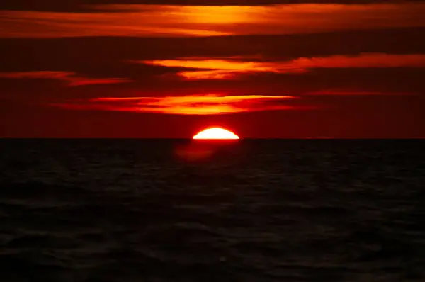 Finlandiya 'nın Pori kentindeki Bothnian Denizi kıyısında bulutlu batan güneş kırmızıya boyandı.