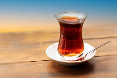 Elinde kaşıkla çay bardağında Türk çayı.