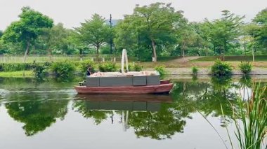 Jakarta, Endonezya, 27 Haziran 2025: PIK 2 (Pantai Indah Kapuk) dar bir nehir boyunca yavaşça yüzen küçük bir tekne. Sakin sular ve doğal yansımalarla çevrili..