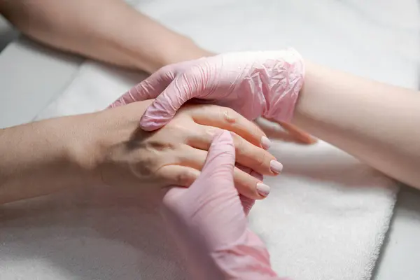 Close-up hands beautician, womans hands receive manicure treatment, master makes a hand massage in a beauty salon. Spa nail and hand care concept