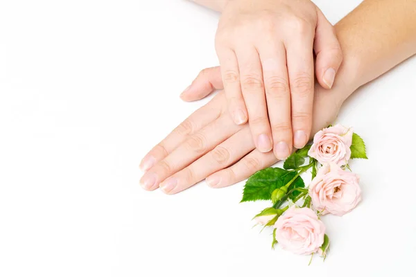 Beauty womans hand with rose flowers lies on the table, white background. Natural beauty product and hand care, moisturizing and wrinkle reduction, skin care