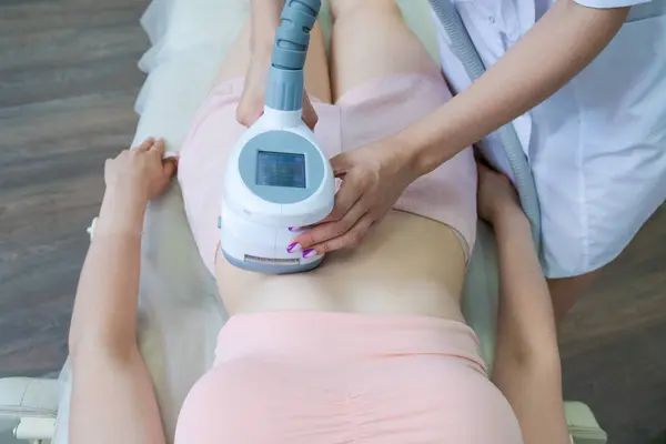Vacuum massage apparatus. Anti-cellulite body shaping procedure. Apparatus for weight loss. Woman and doctor in medicine salon. Hardware massage in a beauty salon
