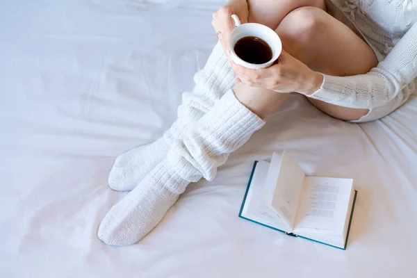 Beauty portrait relaxed woman in morning and drinking coffee in bed. Attractive woman is reading a book and bed. Caucasian young woman relaxed in bed and reads a book