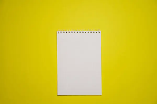 Notebook mockup with blank white blank for design and advertising. Notepad with chrome spring and free copy template. On a yellow background.