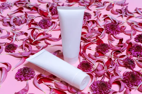 Natural cosmetic products with white bottles and fresh flowers on pink background, Beauty and skin, hair or body care concept, space for mockup