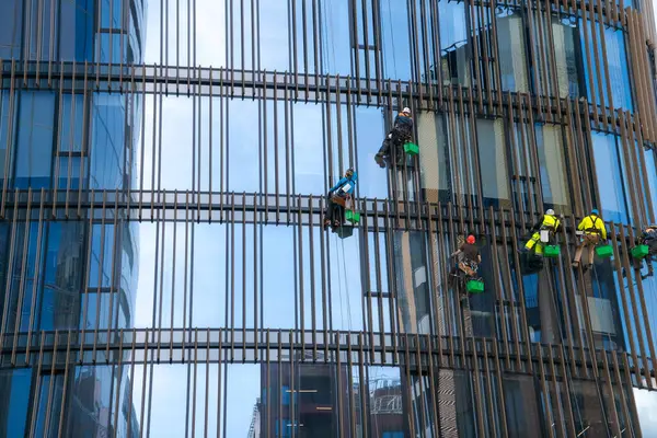 Window cleaners wash the glass of an office building at a height