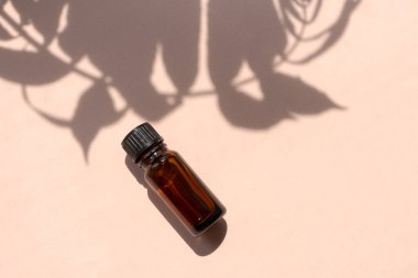 Masanın üzerinde bir şişe gerekli yağ duruyor. Şişesi kahverengi ve siyah kapağı var. Şişenin etrafı yapraklı bitkilerle çevrili. Rahatlama ve sakinlik kavramı