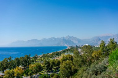 Bereketli yeşil bir manzaraya, uzak dağlara ve açık mavi gökyüzüne sahip kıyı şehirleri. Deniz kenarı, tatil, doğa.