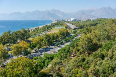 Yeşillik, bakımlı bir park ve arka planda görkemli dağların yer aldığı manzaralı bir sahil kenti. Güzel doğa ve şehir hayatı kavramı